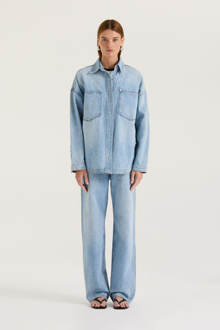 Model wearing a light blue denim jacket  and light blue denim jeans on a white background