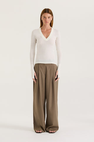 Model wearing a white long-sleeve top and taupe wide-leg pants on a white background