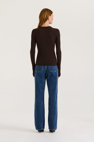Back view of a model wearing a chocolate long-sleeve top and blue jeans on a white background