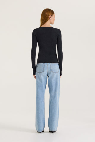 Back view of a model wearing a charcoal long-sleeve scoop top and light blue jeans on a white background