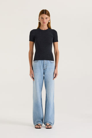 Model wearing a charcoal t-shirt and light blue jeans on a white background