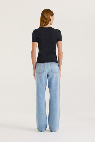 Back view of a model wearing a charcoal t-shirt and light blue jeans on a white background