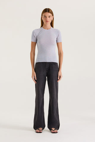 Model wearing a light grey fitted t-shirt and black jeans on a white background