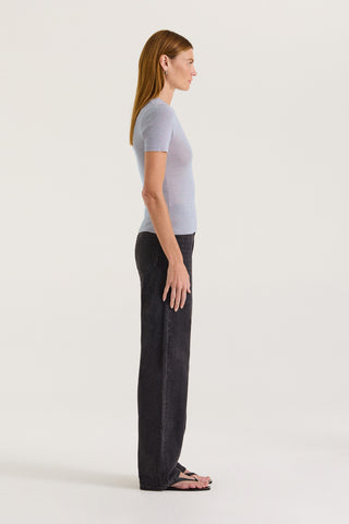 Side view of a model wearing a light grey fitted t-shirt and black jeans on a white background