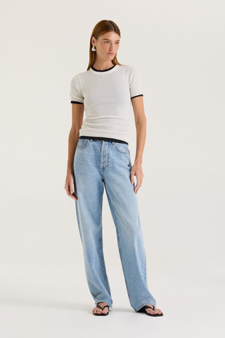 A model wearing a white fitted t-shirt and light blue jeans on a white background