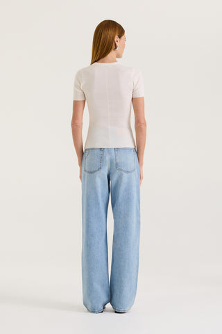Back view of a model wearing a white fitted t-shirt and light blue jeans on a white background
