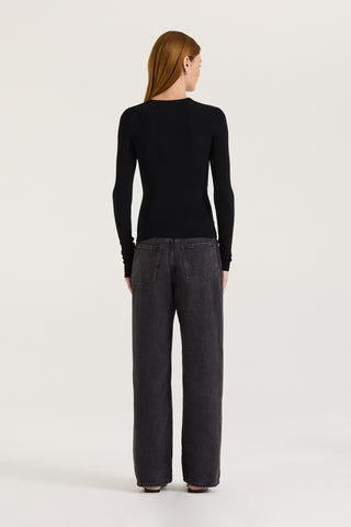 Back view of a model wearing a black long-sleeve top and black wide-leg jeans on a white background 