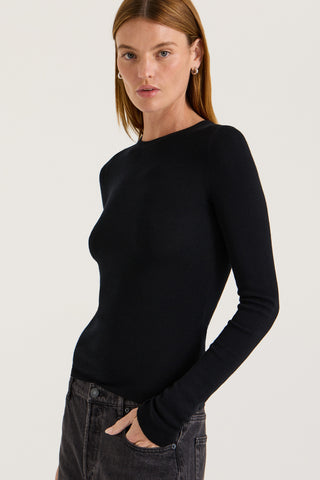 Model wearing a black long-sleeve top against a light background