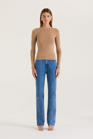 Model wearing a tanned long sleeve top and blue jeans with a white background