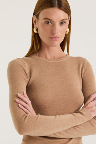Close up view of a model wearing a tanned long sleeve top with a white background