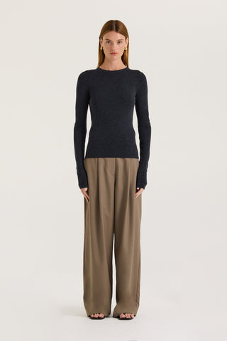 Model wearing a charcoal long sleeve top and taupe pants on a white background
