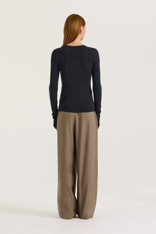 Back view of a model wearing a charcoal long sleeve top and taupe pants on a white background