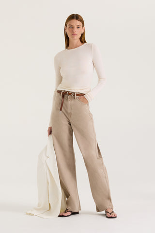 Model wearing a white long sleeve top and tan wash jeans on a white background