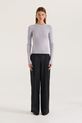 Model wearing a light grey long sleeve top and black pants on a white background