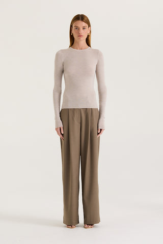 Model wearing a light grey long sleeve top and taupe pants against a white background