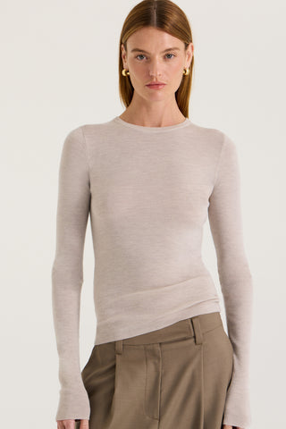 Close up view of a model wearing a light grey long sleeve top against a white background
