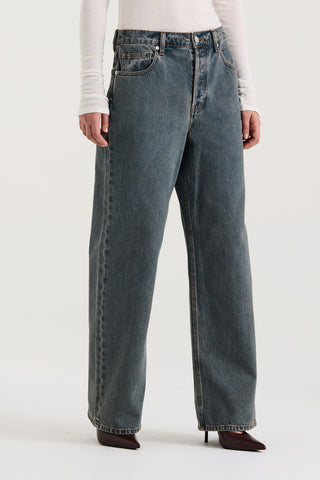 Close up view of model wearing graphite wash wide leg and low rise Henne Gisella Jeans on a white background