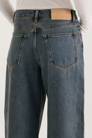 Close up back view model wearing graphite wash wide leg and low rise Henne Gisella Jeans with Henne leather patch on a white background