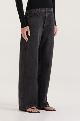 Close view of model wearing black wash wide leg and low rise Jeans on a white background 