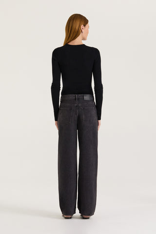 Back view of model wearing black wash wide leg, low rise Jeans with a black long sleeve top on a white background 