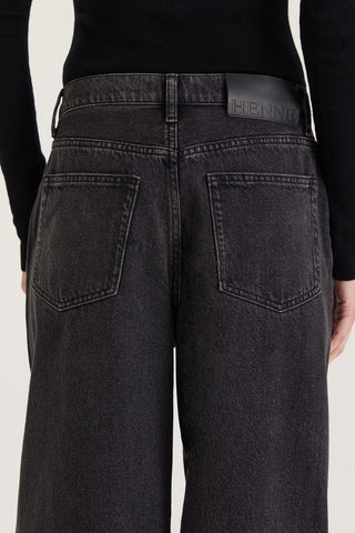 Close up back view of model wearing black wash wide leg and low rise with Henne leather patch on a white background 