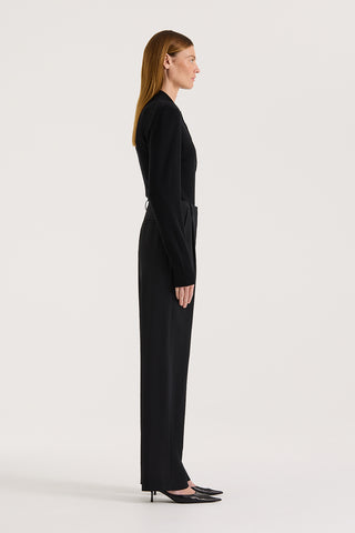 Side view of a model wearing high rise wide leg pants and a black long sleeve knit on a white background