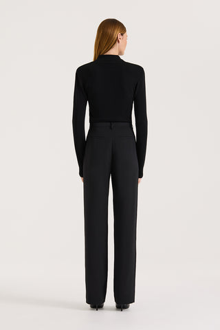 Back view of a model wearing high rise wide leg pants and a black long sleeve knit on a white background
