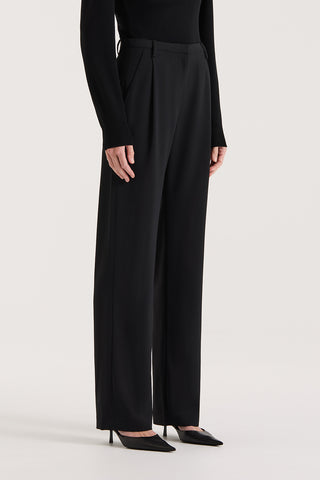 Model wearing high rise wide leg pants on a white background