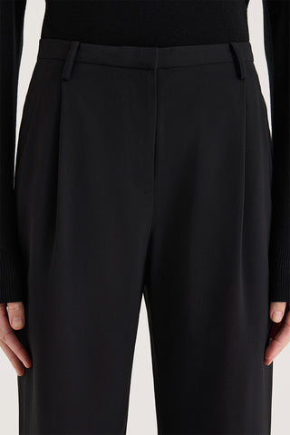 Close up view of a model wearing high rise wide leg pants on a white background