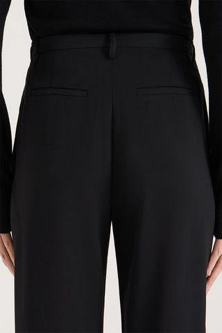 Close up back view of a model wearing high rise wide leg pants on a white background