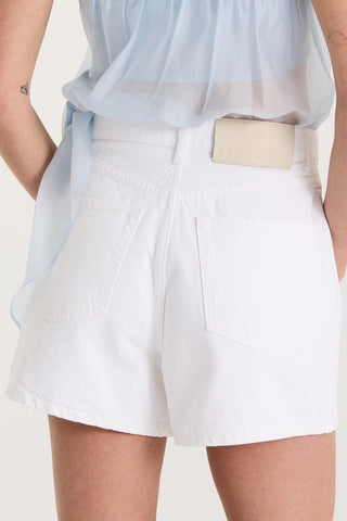 Close up back view of model wearing white shorts with a Henne leather patch on a white background