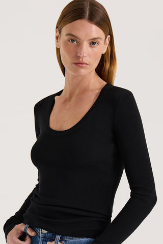 Close up view of a model wearing a black scoop neck long sleeve top on a white background