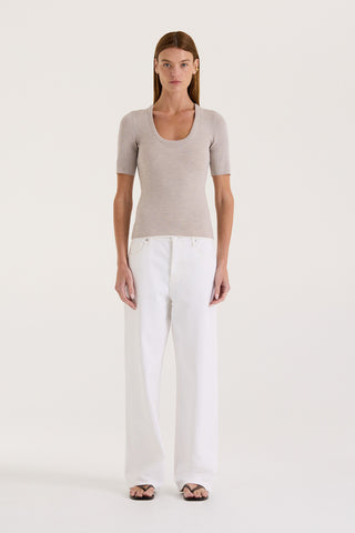 Model wearing a light grey fitted t-shirt and white wide-leg jeans on a white background