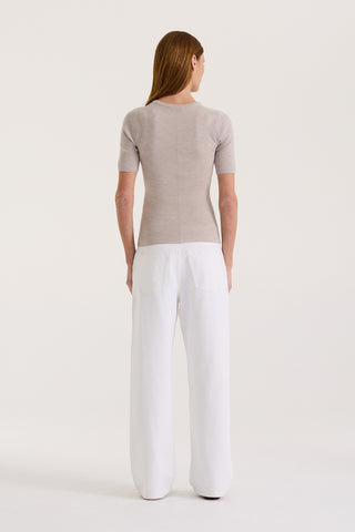 Back view of a model wearing a light grey fitted t-shirt with a white wide-leg jeans on a white background