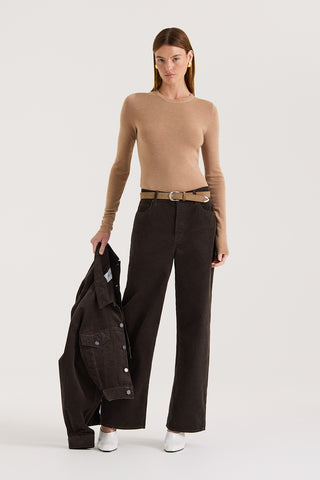 Model wearing a beige long sleeve top and chocolate cord jeans holding a chocolate cord jacket on a white background