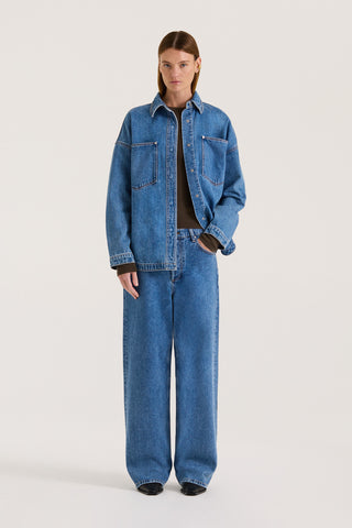 Model wearing a indigo wash denim jacket with the matching denim jeans on a white background