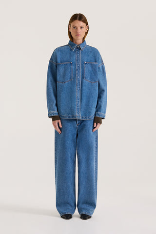 Model wearing a indigo wash denim jacket with the matching denim jeans on a white background