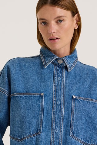 Close up view of a model wearing an indigo wash denim jacket on a white background