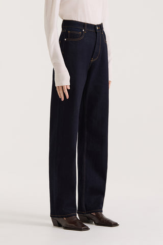 Model wearing dark indigo high rise, straight leg jeans on a white background