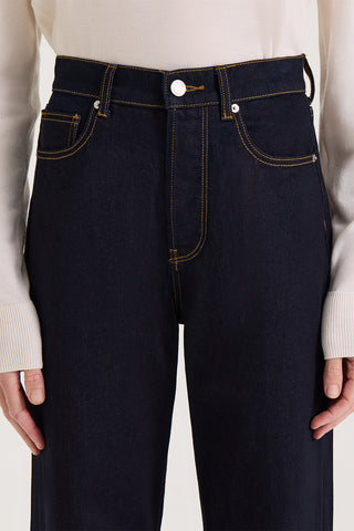 Model wearing dark indigo, straight leg, high rise jeans on a white background