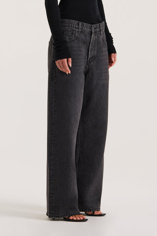 Model wearing black wide-leg jeans on a white background