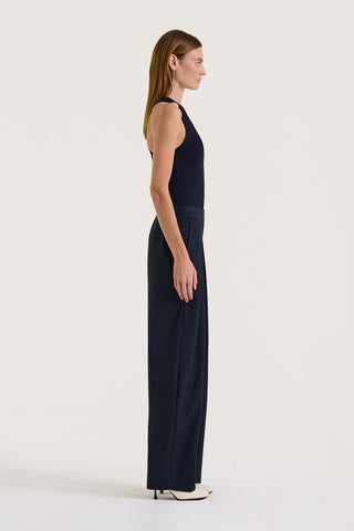 Side view of a model wearing a Navy tank top and Navy wide-leg pleated pants on a white background