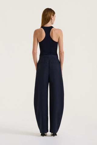 Back view of a model wearing a Navy tank top and Navy wide-leg pleated pants on a white background