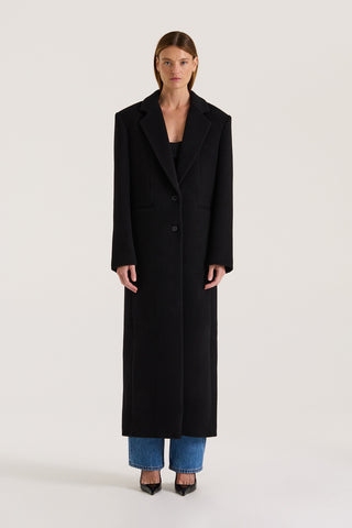 Model wearing a black coat on a white background