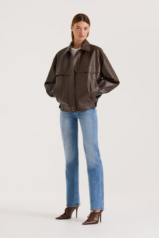 Model wearing a chocolate leather-effect jacket and blue jeans against a white background.