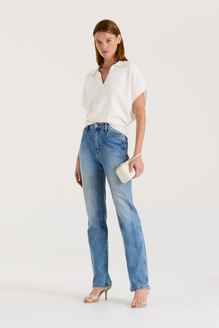 Model wearing a white loose fitting t-shirt and blue high rise, straight leg jeans on a white background