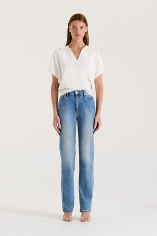 Model wearing a white loose fitting t-shirt and blue high rise, straight leg jeans on a white background