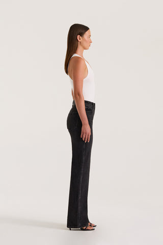 Side view of model wearing Black Slim fitted jean and a fitted white tank top on a white background