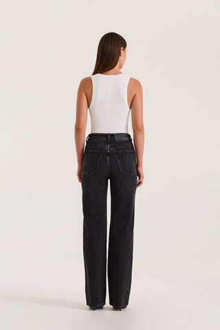 Back profile of model wearing Black Slim fitted jean and a fitted white tank top on a white background
