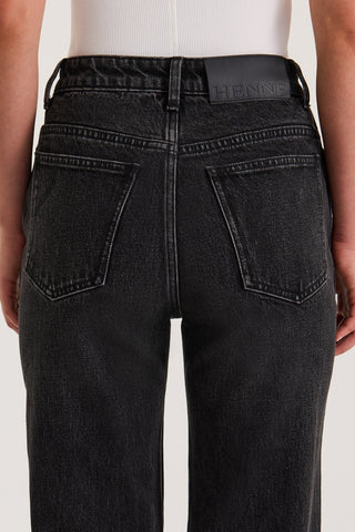 Close up back view of model wearing Black slim fitted Jeans with a Henne leather patch on a white background